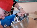 6. Chłopiec z pomocą nauczycielki dodaje cukier 