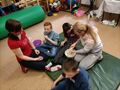 uczniowie dotykaja masy plastycznej, siedzą na materacu razem z nauczycielkami