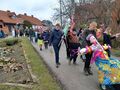 Uczniowie maszerują ulicą. Na pierwszym planie widać marzanne. Uczniowie trzymają w rękach kolorowe gaiki 