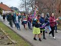 Uczniowie maszerują ulicą. Uczniowie trzymają w rękach kolorowe gaiki 