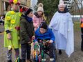 Uczniowie pozują do zdjęcia z uczennicami przebranymi za Panią Wiosnę i Panią Zimę. Znajdują się w parku w tle widać budynek szkoły 