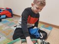 chłopiec siedzi na dywanie i otwiera prezent