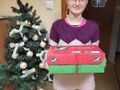 dziewczynka uśmiecha się i trzyma prezent w tle choinka