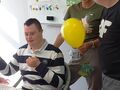 Uczeń jubilat siedzi przy urodzinowym stole z boku stoi nauczycielka z uczniem