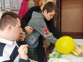 Uczeń podczas swoich urodzin siedzi przy stole z gośćmi