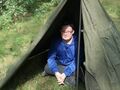 harcerz siedzi pod namiotem zrobionym z pałatki