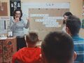 8. Uczestnicy lekcji oceniają zajęcia, dwie nauczycielki stoją z przodu, uczniowie z tyłu siedzą na krzesłach