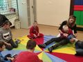 5. Uczniowie siedzą na chuście w kole i podają sobie piłkę 