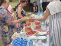 rodzice otrzymują od nauczycielki swieże owoce ze stołu na którym są owoce wody w butelkach talerze filiżanki