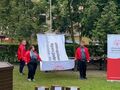 zawodnicy wciągają flagę na masz są ubrani w czerwone bluzy