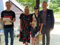 Zawodnik trzyma puchar obok prowadzący zawody Pani Dyrektor oraz Naczelnik Wydziału Edukacji Kultury i Sportu