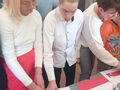 Na zdjęciu widzimy ucznia razem z nauczycielką. Chłopiec układa flagę Polski 