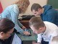 Zdjęcie przedstawia uczniów oraz panie. Dzieci rozwiązują zadania wykorzystując komputer oraz tablet 