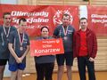 zawodnicy wraz z trenerem stoją przed banerami olimpiad specjalnych i pozują do zdjęcia grupowego, zawodniczka trzyma w dłoniach tablicę SOSW Konarzew