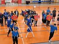 reprezentacje klubów stoją ustawieni na ceremoni otwarcia na hali sportowej przed nimi występ grupy tanecznej w niebieskich strojach