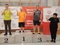zawodnicy stoją na podium obok stoi pani