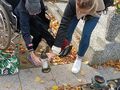 2. Uczennica z pomocą nauczyciela odkłada znicz na grób 