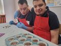 uczniowie patrzą na ciasto wlane do foremek na muffinki