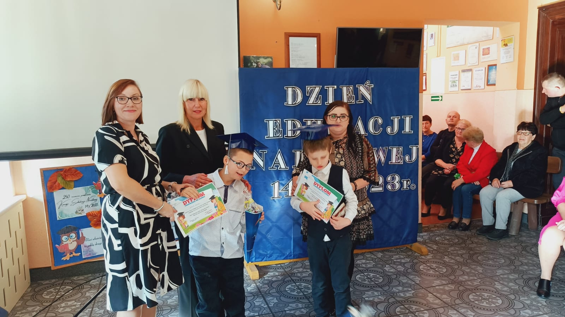 nauczyciele wraz z Panią dyrektor i uczniami stoją w holu szkoły