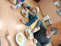11. Uczniowie siedzą przy stoliku i zajadają spaghetti 