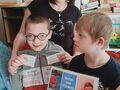 3. Dwoje uczniów wraz z nauczycielem uczeń trzyma wylosowaną karteczkę z miłą treścią 