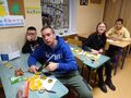 dzieci siedzą w ławkach i dekorują ususzone plastry pomarańczy na ozdoby