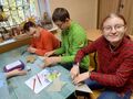 dzieci siedzą w ławkach i przygotowują małe eko choinki z tektury i koronki 2