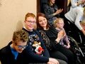 10 uczeń i nauczycielka usmiechają sie do obiektywu obok siedzą inni uczniowie i nauczyciele