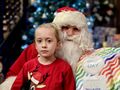 15 dziewczynka siedzi obok mikołaja w tle choinka