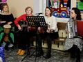 3 nauczycielki siedzą w holu i grają na instrumentach bębenku gitarze akordeonie