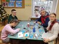uczniowie siedzą w klasie przy stole i wycinaja z papieru karmniki dla ptaków