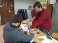 jeden uczeń szlifuje drewno za pomocą papieru ściernego dwóch uczniów skręca karmnik za pomocą wkrętarki