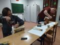 jeden z uczniów maluje karmnik drugi uczeń za pomocą wkrętarki skręca karmnik