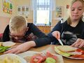 2. Uczennica smaruje chleb masłem obok siedzi kolega 