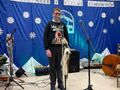 7.uczestnik konkursu podczas występu na sceniez tyłu na granatowym tle napis XV Międzyszkolny Konkurs Kolęd Pastorałek i Pieśni Zimowych