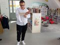 Zdjęcie przedstawia chłopca który znajduje się w bibliotece. Uczeń czyta wiersz 