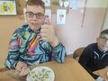 chłopiec siedzi przy stole przed nim knedliczki na talerzu obok siedzi drugi chłopiec