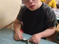 uczen siedzi w ławce i lepi z plasteliny różne kształty