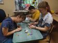uczniowie siedza w klasie i tworzą rybki z papieru do kacika przyrodniczego