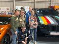 uczniowie pozują przy samochodach na targach motoryzacyjnych
