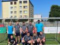 Uczniowie naszej szkoły razem z dwoma opiekunami pozują do zdjęcia na tle bramki piłkarskiej. 