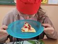 9. Dziewczynka prezentuje kawałek pizzy 