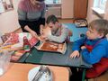 uczeń z pomocą nauczyciela nakłada dodatki na pizze