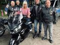 Pani Dyrektor siedzi na motocyklu obok stoją Panowie motocykliści