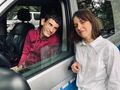 Pani stoi obok samochodu policyjnego w którym siedzi uczeń