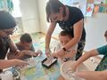 Uczniowie robią masę plastyczną z pomocą nauczycieli