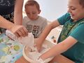 uczeń robi masę plastyczną z pomocą nauczyciela