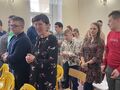 9.uczniowie i nauczyciele stoją w sali i śpiewają