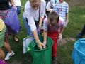 uczeń z pomocą nauczyciela wkłada śmieci do odpowiedniego worka