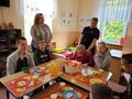 2. Uczniowie siedzą przy stole dwie panie stoją 